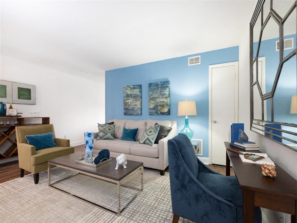 A living room with a blue chair and a glass coffee table.