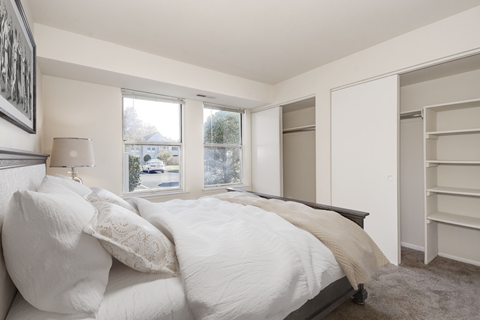 A bedroom with a large bed and a window overlooking a street.