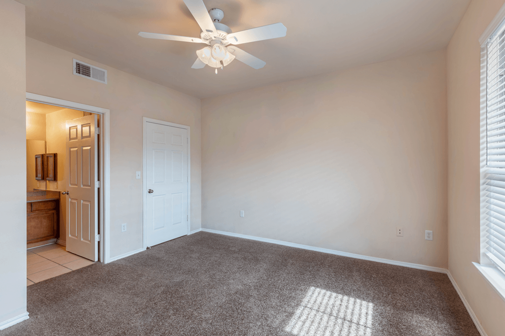 a bedroom with a ceiling fan and a door to a bathroom
