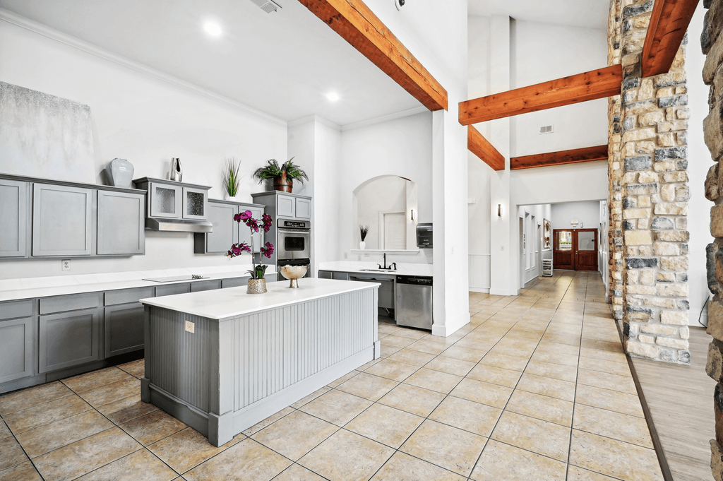 a large kitchen with stainless steel appliances and a stone wall