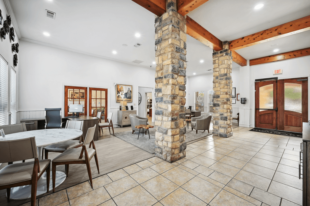 the lobby of a lodge with tables and chairs and a stone column