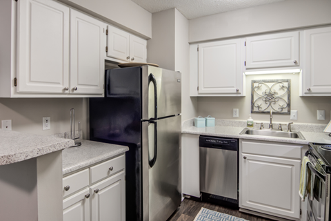 A kitchen with white cabinets and a black fridge.