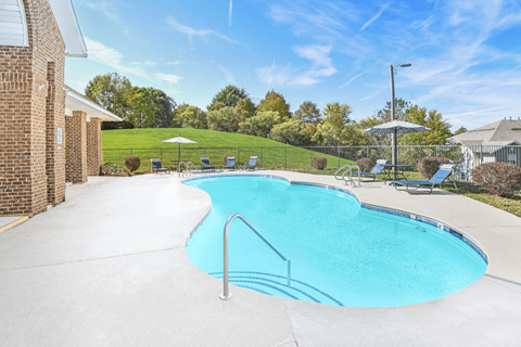 A small residential pool with a white fence and a white umbrella.
