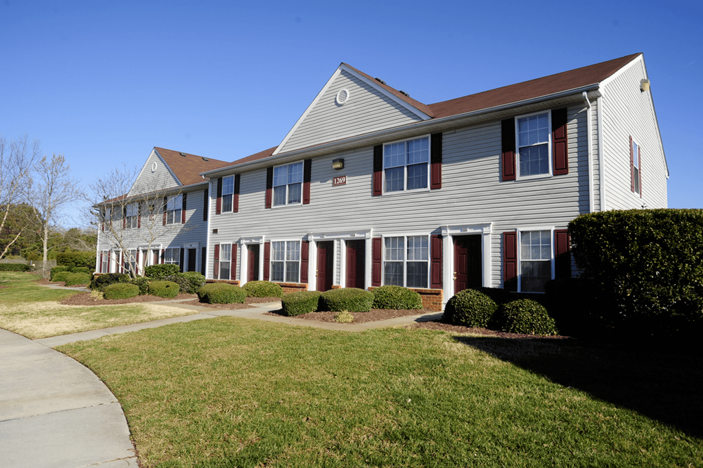 Exterior apartment building with red doors, shutters and roof.