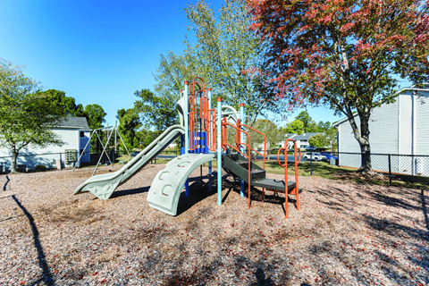 A playground with a green slide and orange climbing frame.