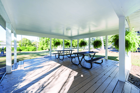 A wooden deck with picnic tables and benches under a white roof.