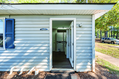 A small white building with a blue door and a sign on the wall.