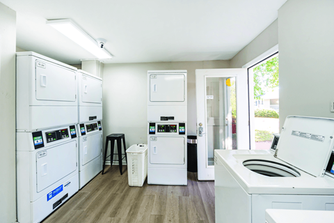 A laundry room with a washer and dryer on the left and a washing machine and dishwasher on the right.