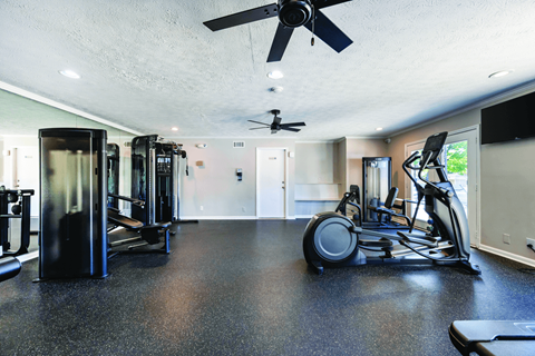 A spacious gym with a variety of equipment including treadmills, elliptical machines, and a stationary bike.