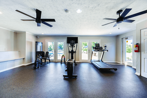 A spacious room with a treadmill, elliptical trainer, and a stationary bike.