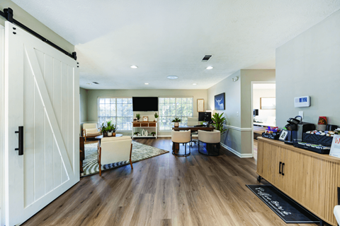 A white door with a black handle is open to a room with wooden floors and furniture.