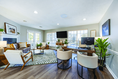 A living room with a fireplace, two chairs, a couch, a desk, and a television.