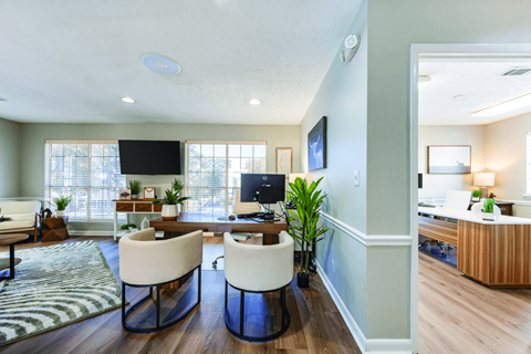 A modern living room with a television, two chairs, and a coffee table.