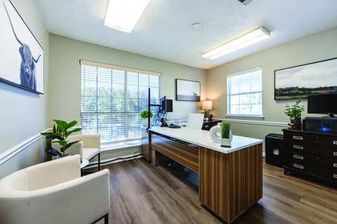 A room with a desk, chairs, and a television.