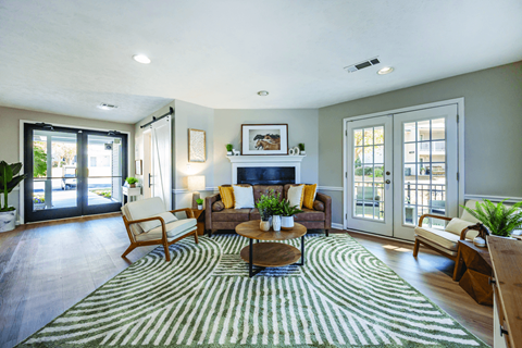 A living room with a rug on the floor and a fireplace with a mantle above it.