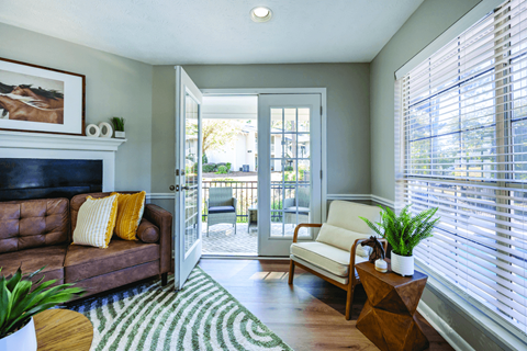A living room with a brown leather couch and a white chair.