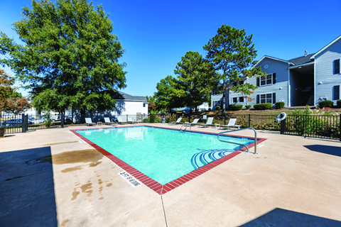 A pool surrounded by trees and a fence.