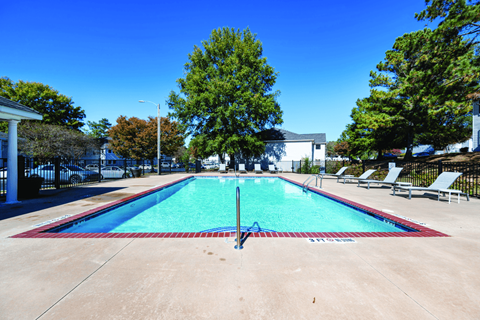 A large swimming pool with a blue water in the middle surrounded by trees.