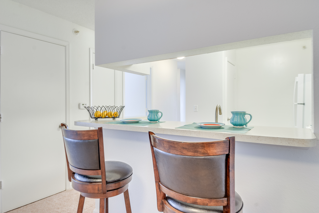 The breakfast bar opens to the kitchen. There are two barstools and place settings for two.