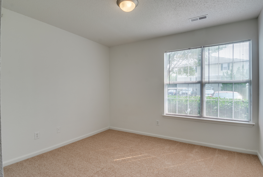 The bedroom has wall to wall carpet and a large picture window.