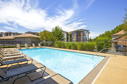 A swimming pool surrounded by lounge chairs and a fence.