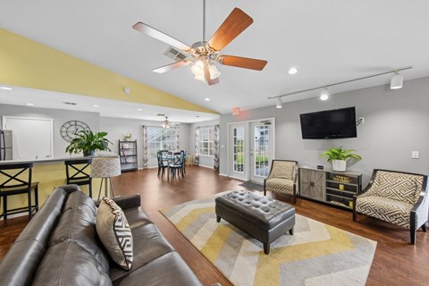 A living room with a brown leather couch and a ceiling fan.