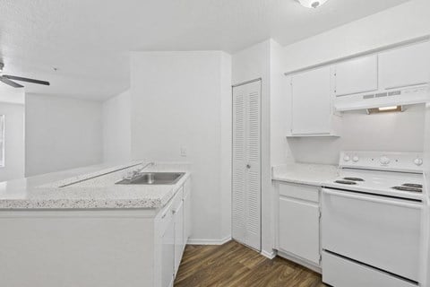 A white kitchen with a sink and stove.