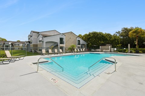 A swimming pool with a slide and lounge chairs in front of a building.