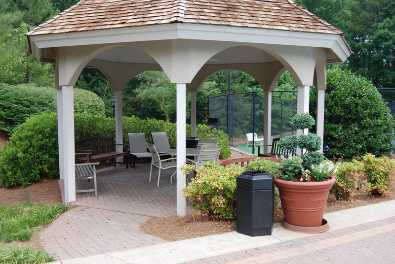a pavilion with a table and chairs in a garden