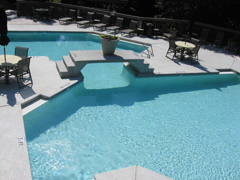 A pool with a waterfall and a planter.