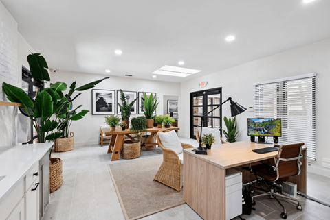 a home office with a desk and plants in the room