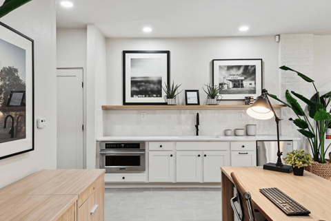A modern kitchen with a wooden table and white cabinets.
