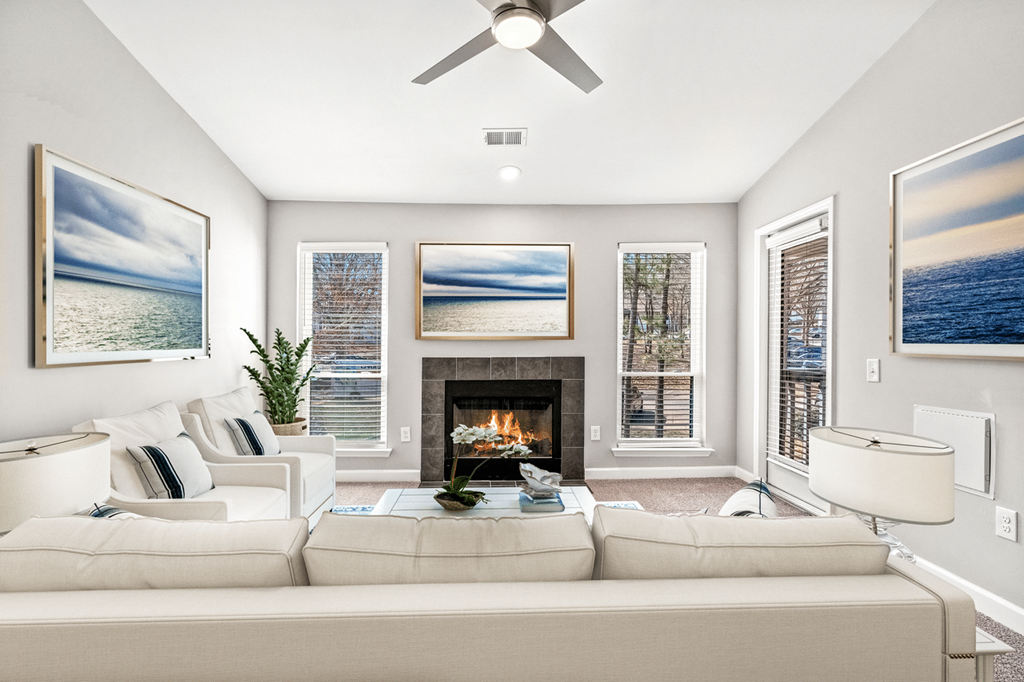 A living room with a fireplace and a painting of a beach scene on the wall at Paces Pointe Apartment Homes, North Carolina
