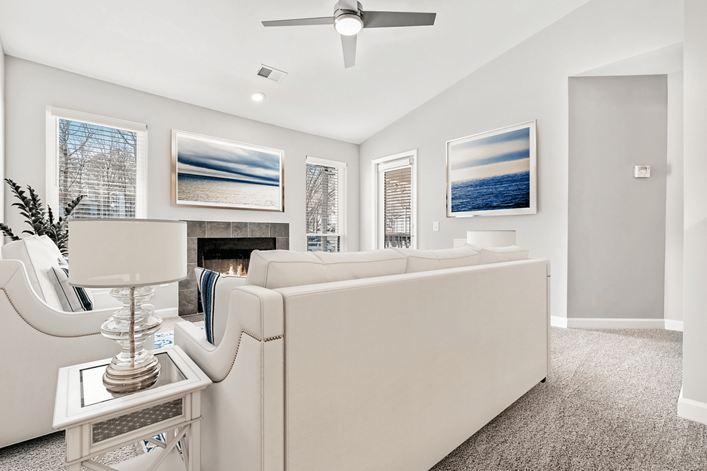 A living room with a white couch and a ceiling fan at Paces Pointe Apartment Homes, Matthews, NC