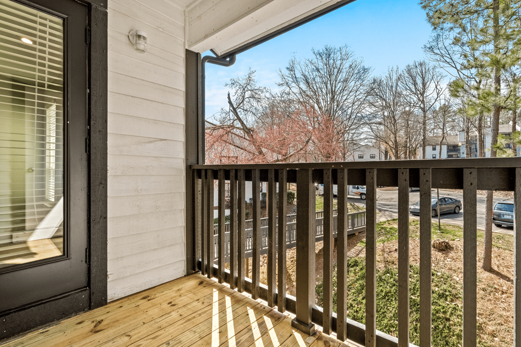 A balcony with a black railing and a view of trees and cars at Paces Pointe Apartment Homes, Matthews