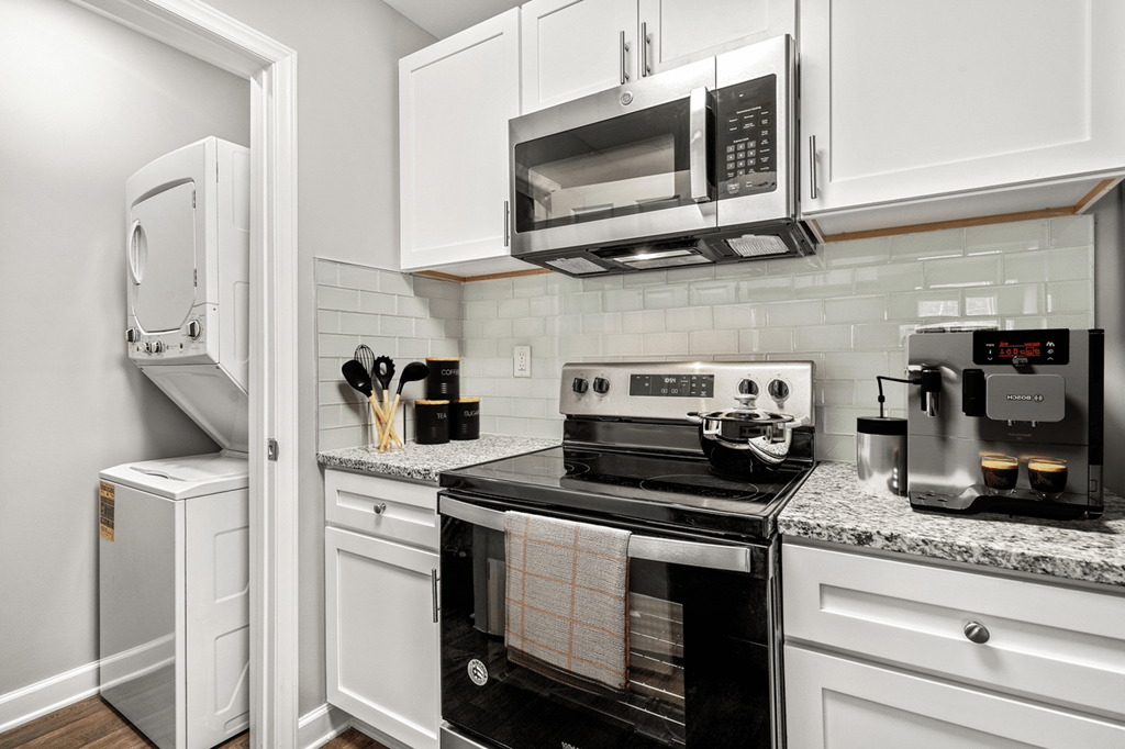 A kitchen with white cabinets and black appliances at Paces Pointe Apartment Homes, North Carolina