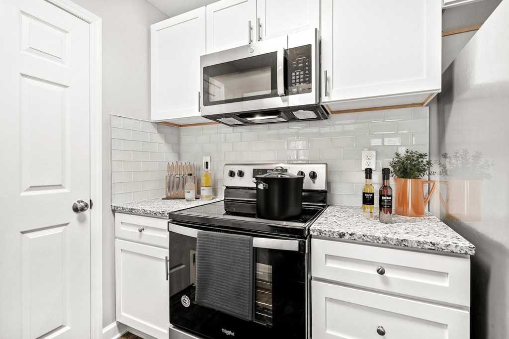 A kitchen with a black stove top oven and white cabinets at Paces Pointe Apartment Homes, Matthews
