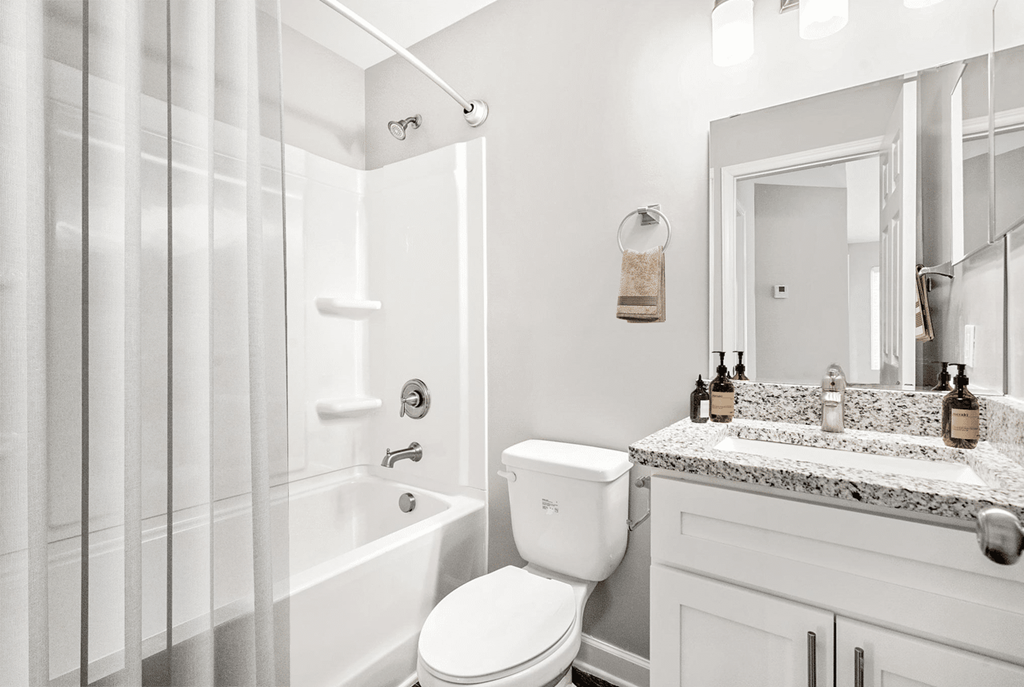 A white bathroom with a toilet, sink, and shower at Paces Pointe Apartment Homes, Matthews, NC, 28105