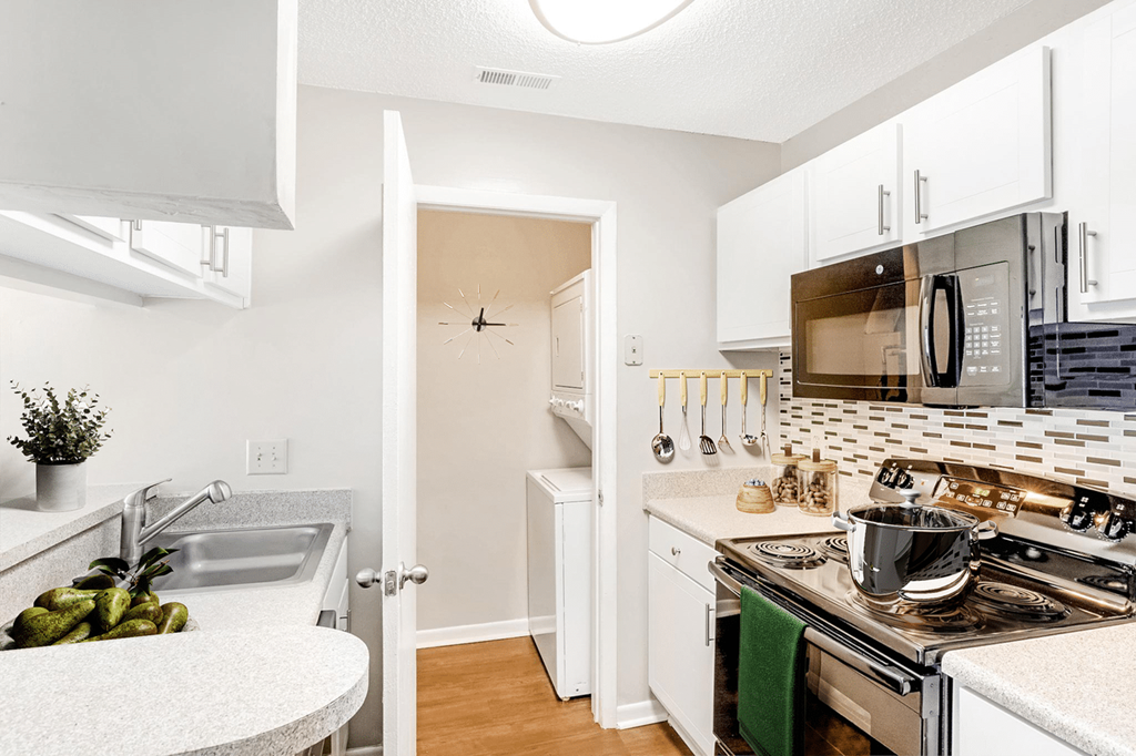 A kitchen with a stove, sink, and cabinets at Paces Pointe Apartment Homes, Matthews, 28105