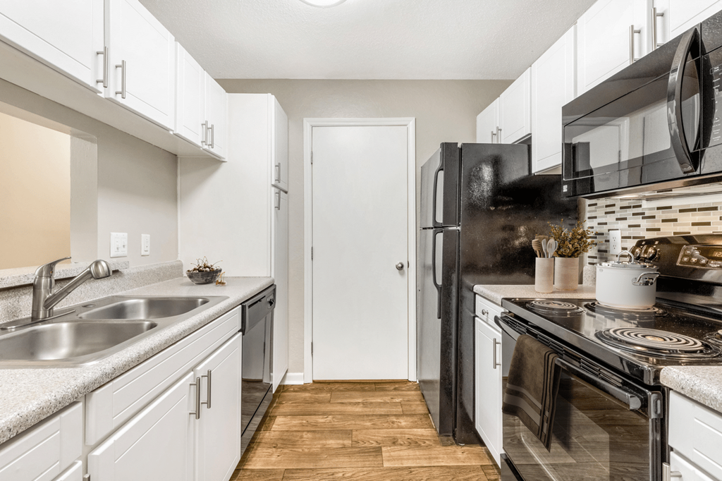 A kitchen with a black refrigerator and white cabinets at Paces Pointe Apartment Homes, Matthews, North Carolina