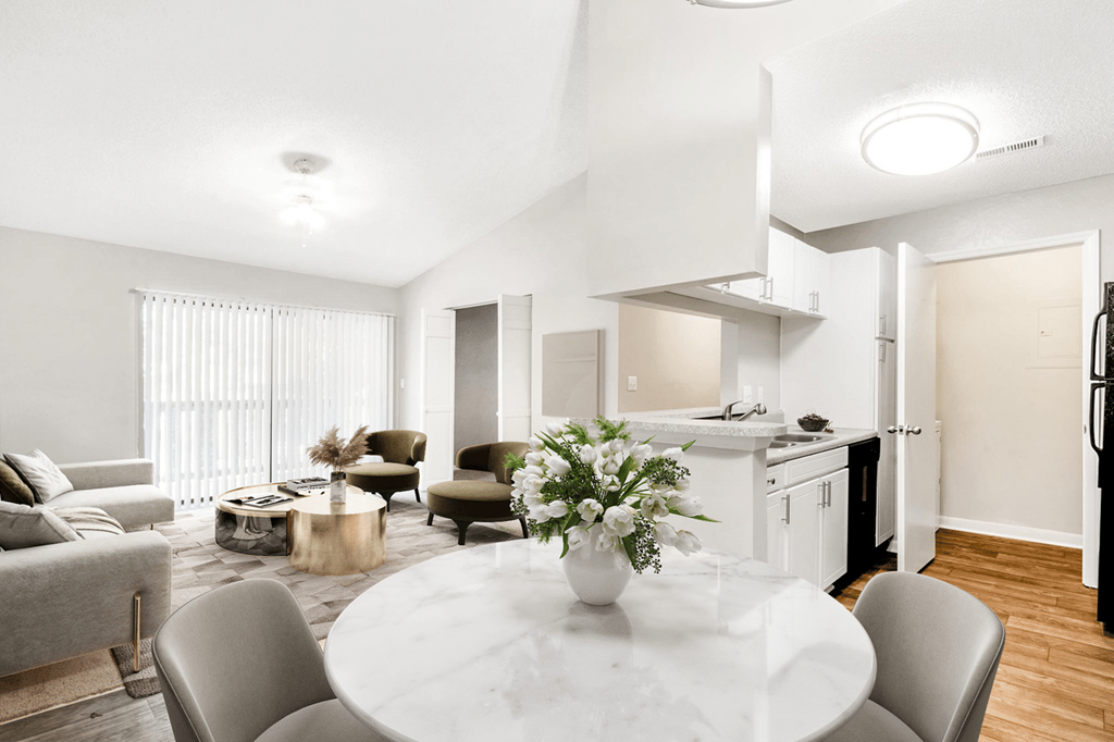 A modern kitchen and living room with a dining table set for two at Paces Pointe Apartment Homes, Matthews