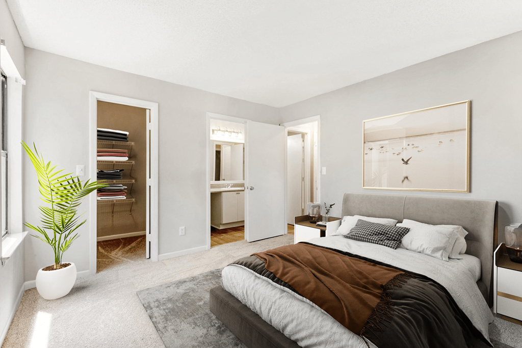 A bedroom with a large bed and a plant in a white pot at Paces Pointe Apartment Homes, Matthews, 28105
