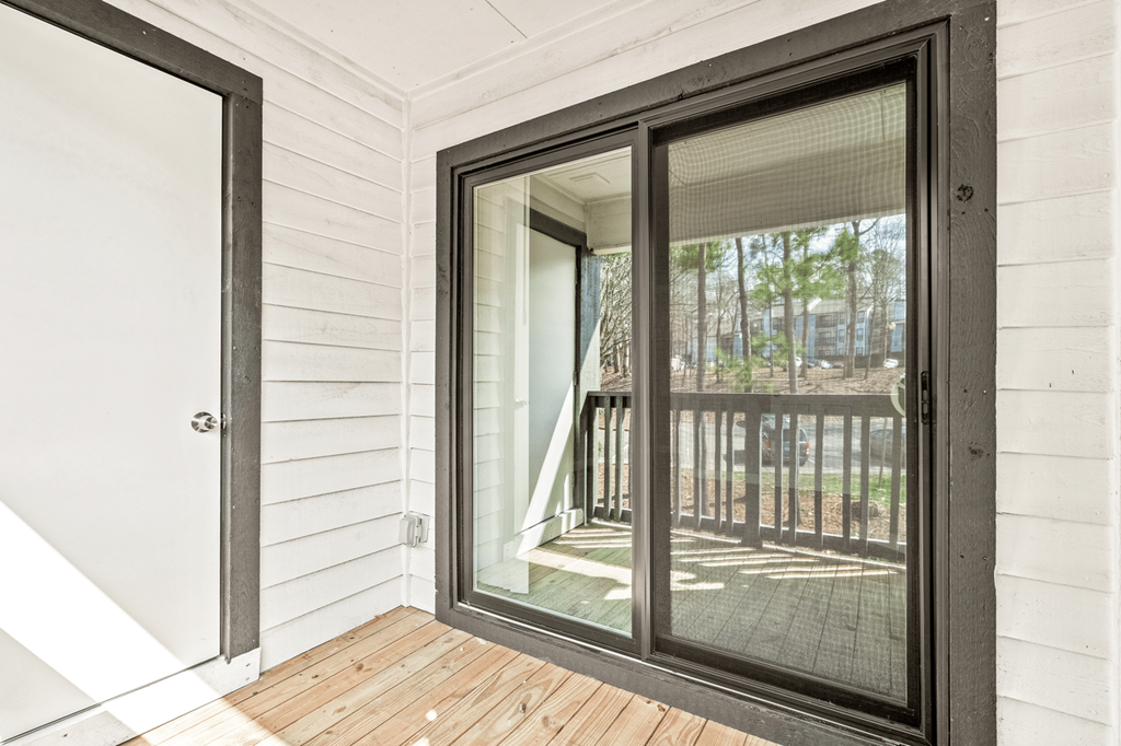 A black screen door is open to a deck at Paces Pointe Apartment Homes, North Carolina, 28105