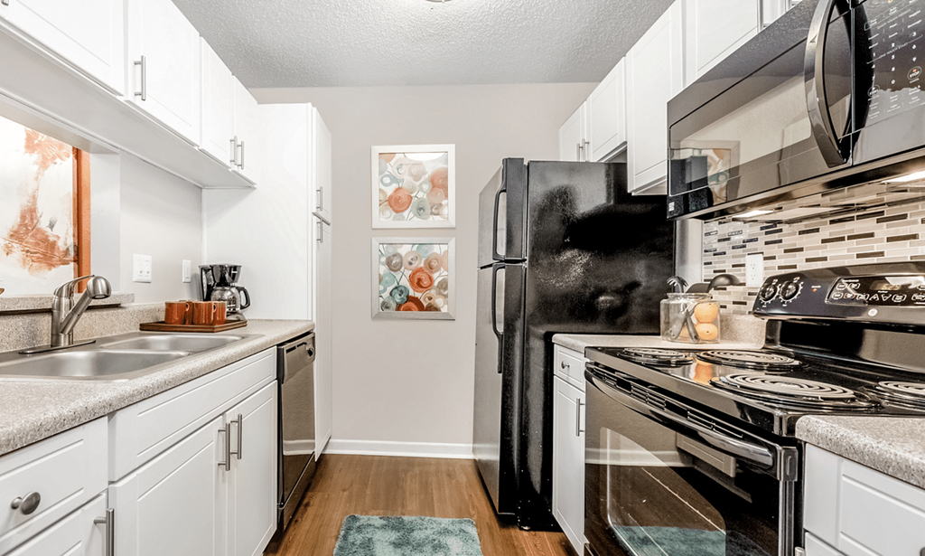 A kitchen with white cabinets and a black refrigerator at Paces Pointe Apartment Homes, North Carolina, 28105