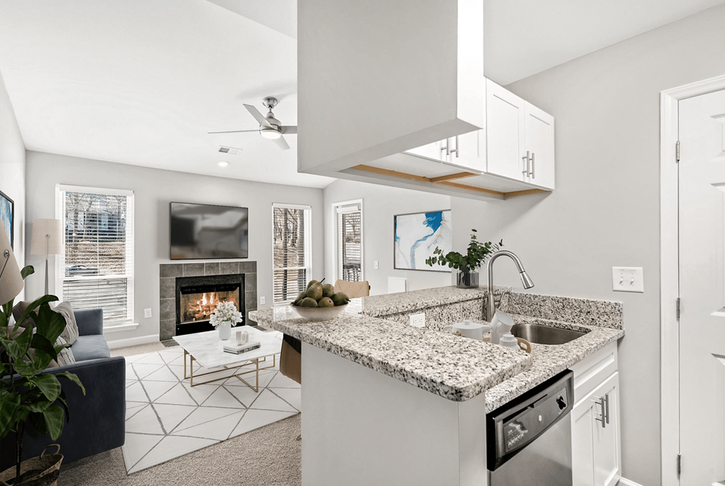 A modern kitchen with a fireplace and a blue sofa at Paces Pointe Apartment Homes, Matthews, NC, 28105