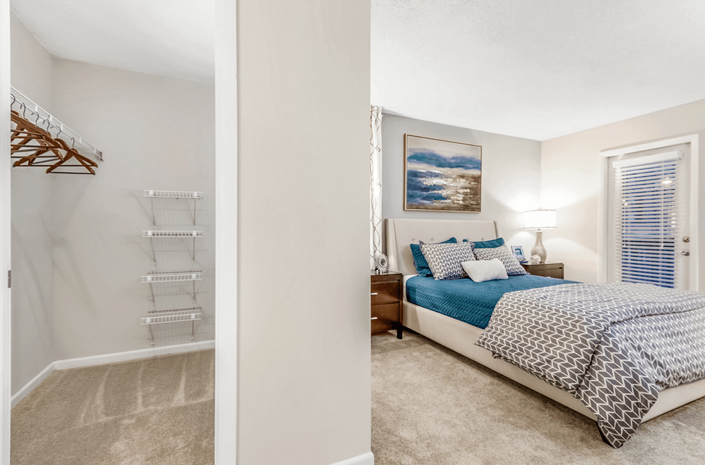 A bedroom with a bed, pillows, a nightstand, and a painting on the wall at Paces Pointe Apartment Homes, Matthews, NC, 28105