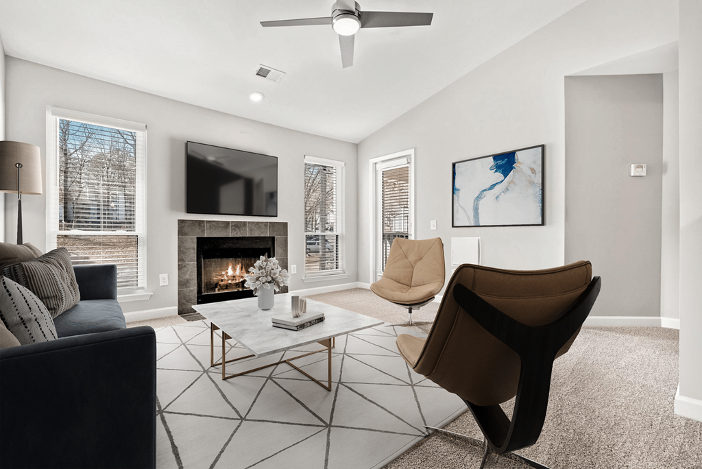 A living room with a fireplace, two chairs, and a coffee table at Paces Pointe Apartment Homes, North Carolina
