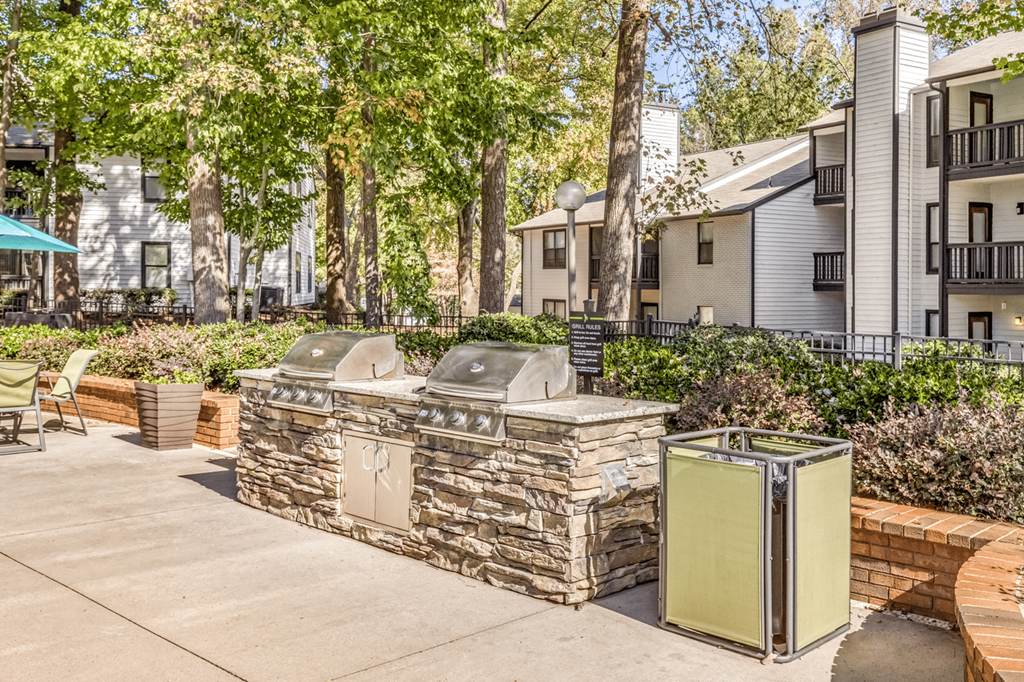 A stone wall with a metal gate in front of a building at Paces Pointe Apartment Homes, North Carolina, 28105