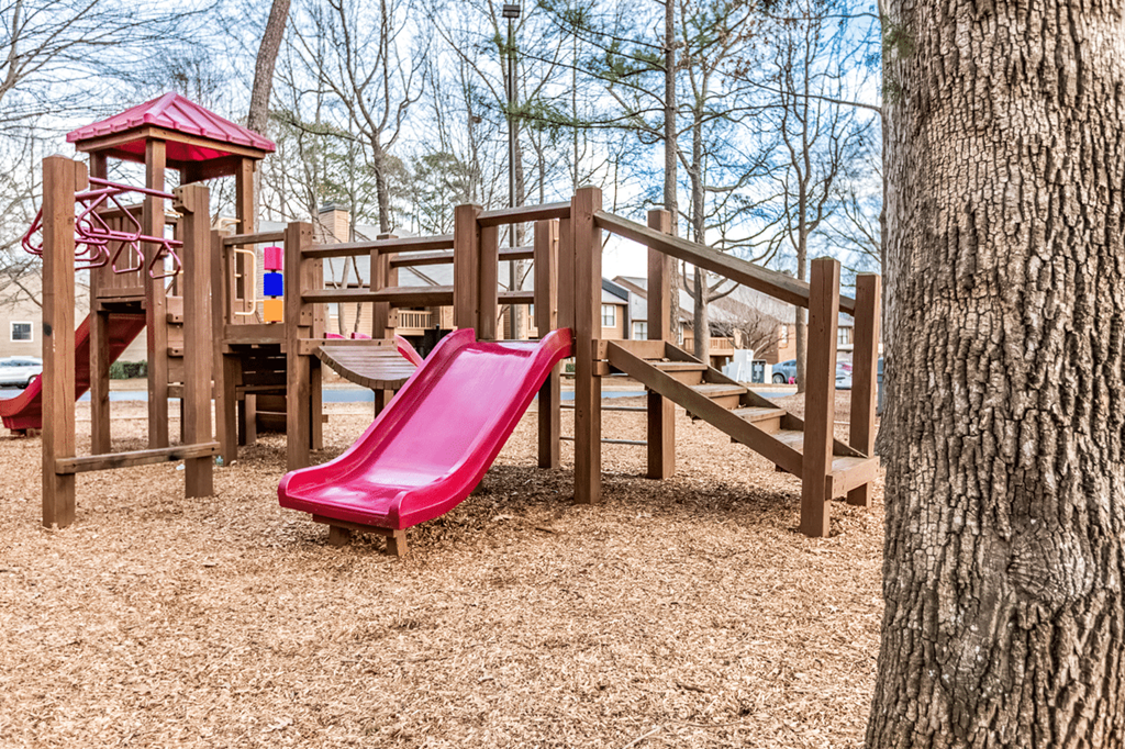 A playground with a red slide and wooden structure at Paces Pointe Apartment Homes, Matthews, NC, 28105