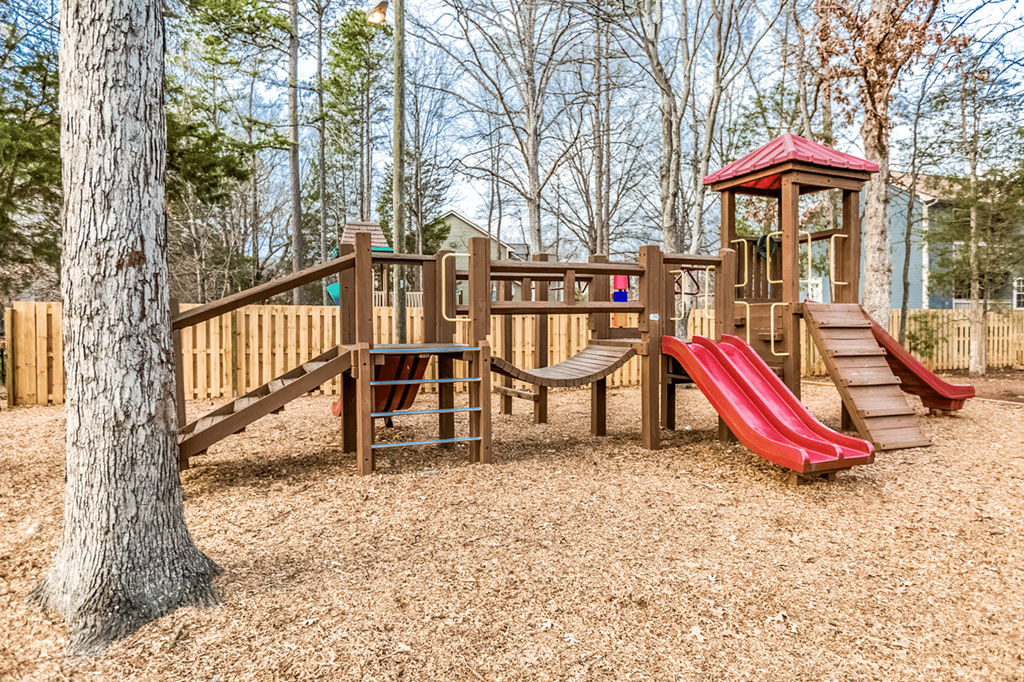 A playground with a red slide and a wooden structure at Paces Pointe Apartment Homes, Matthews